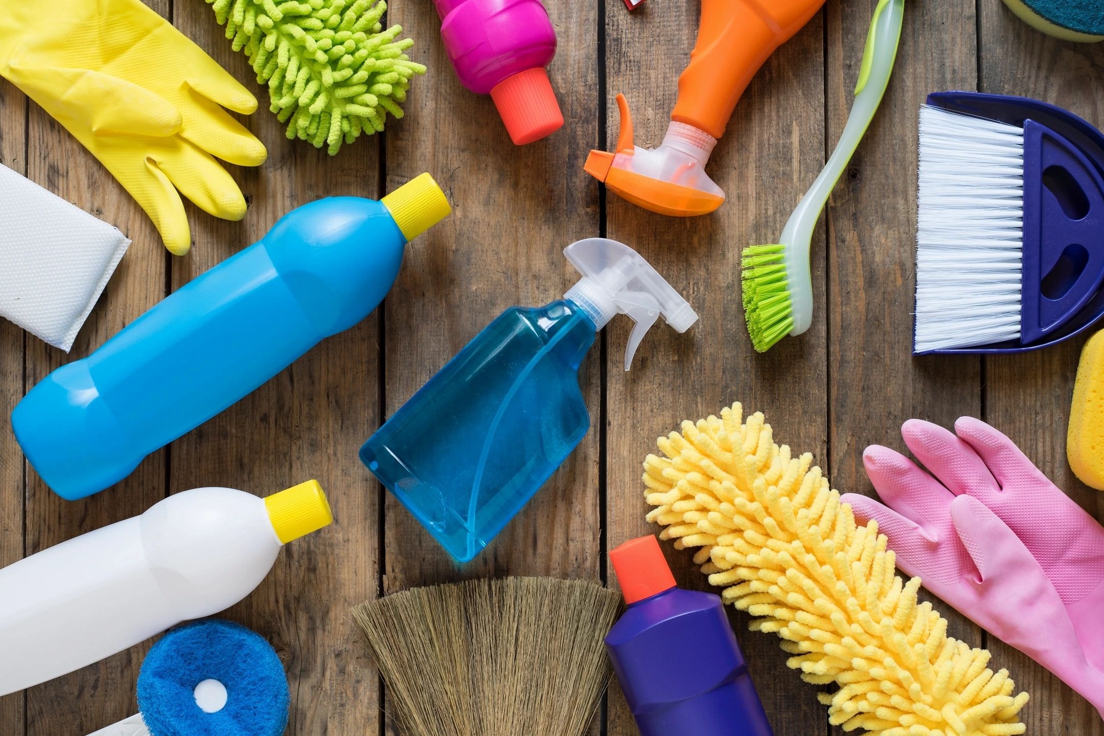 Colorful cleaning supplies arranged on a wooden surface